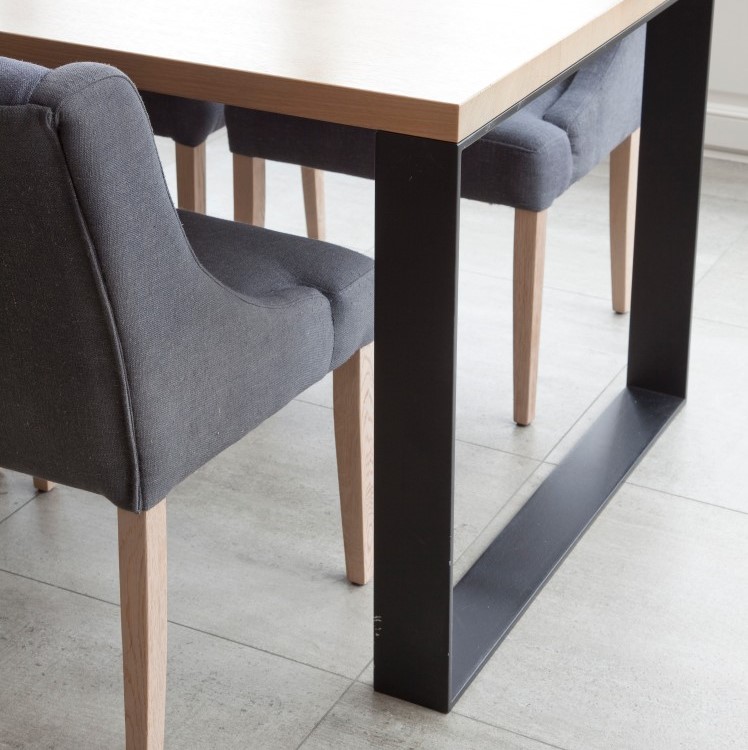 Detail van houten eettafel met zwart onderstel en grijze stoelen
