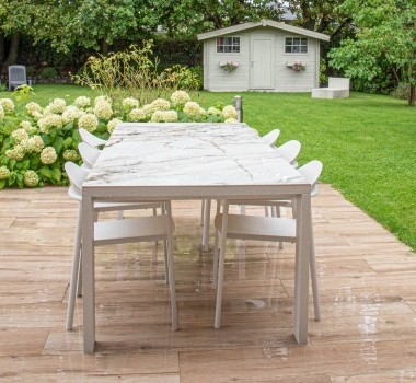 Tuinterras met marmeren tafel en witte stoelen bij tuinhuis