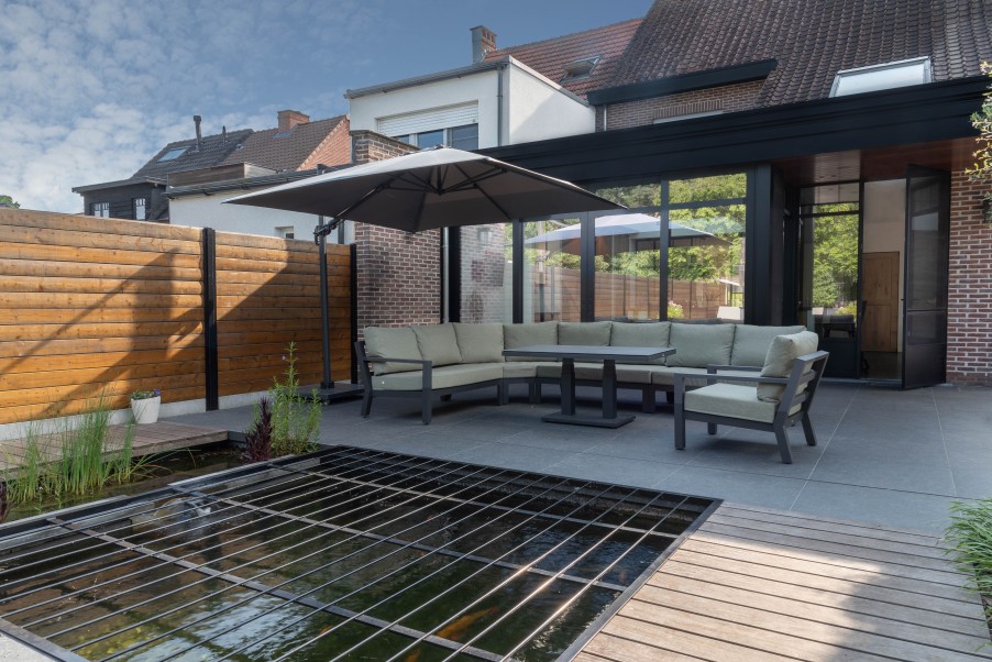 Tuinterras met loungeset onder parasol naast vijver