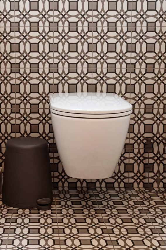 Toilet met bruin-wit gepatroneerde tegels op wand en vloer