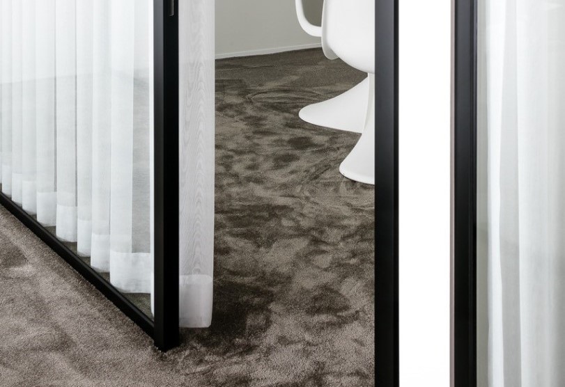 Kantoorruimte met grijs tapijt witte stoelen en glazen wand