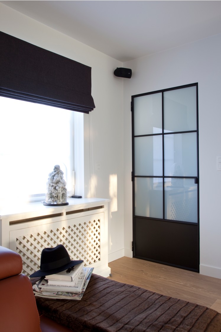 Woonkamer met zwarte stalen glasdeur en radiatorombouw