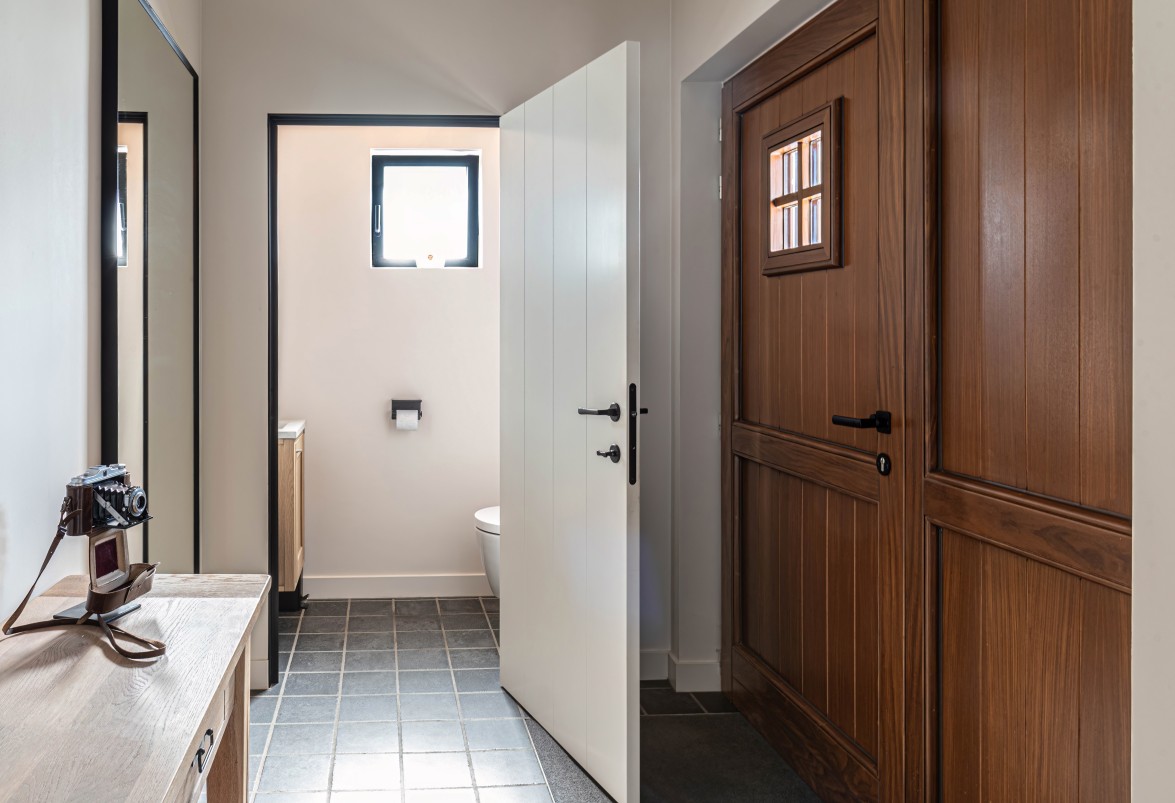 Hal met witte en donkerhouten deur naar toilet