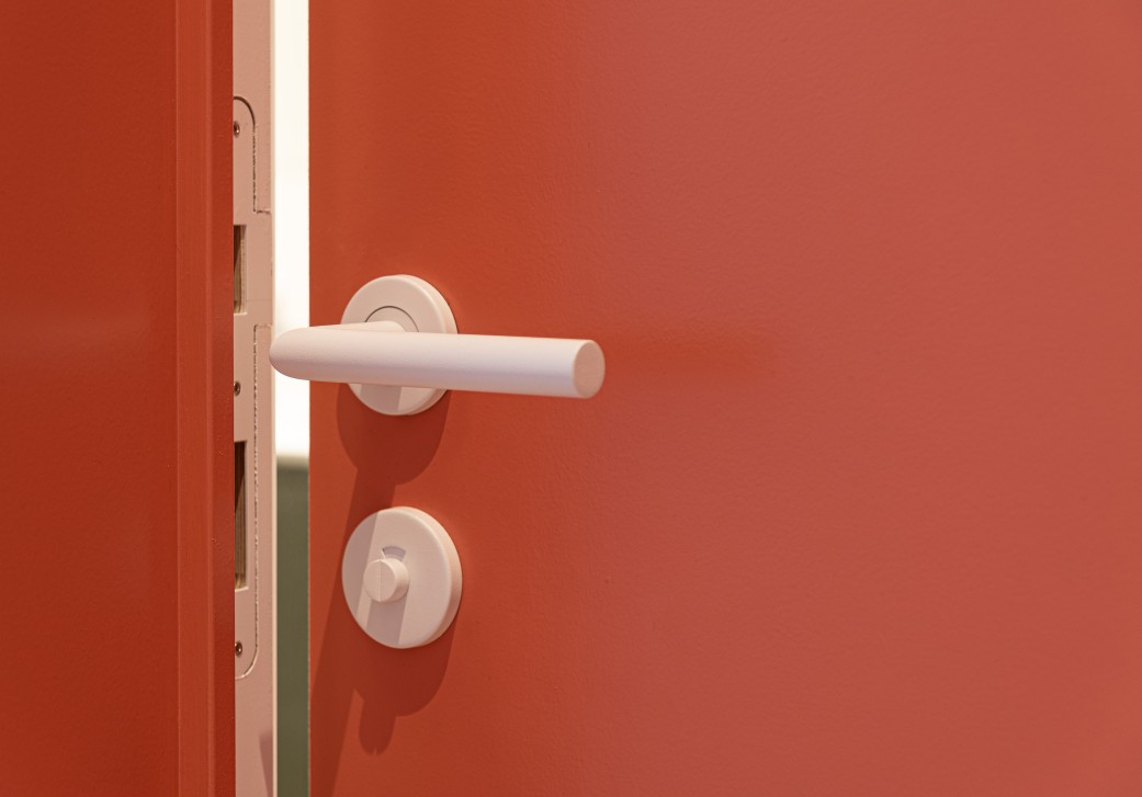 Detail van roestbruine deur met witte deurklink