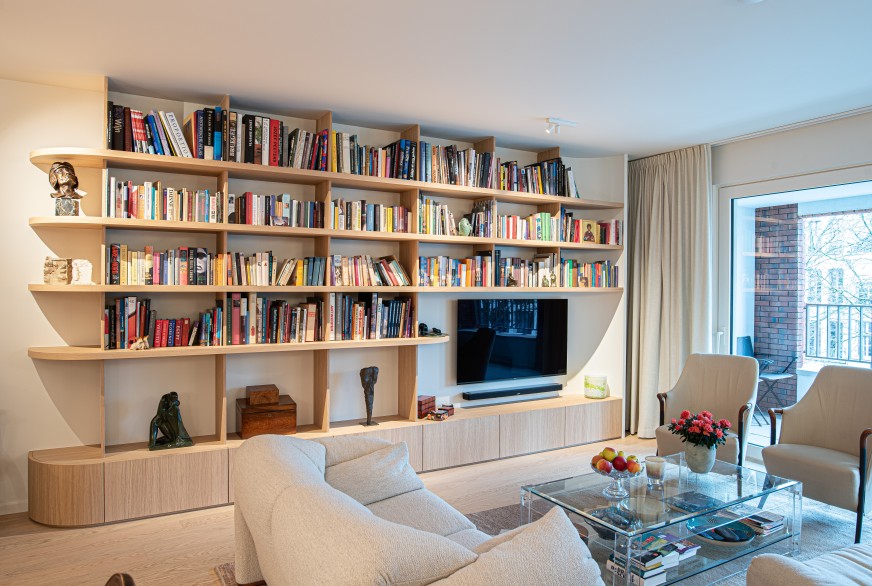 Woonkamer met grote houten boekenkast op maat en tv
