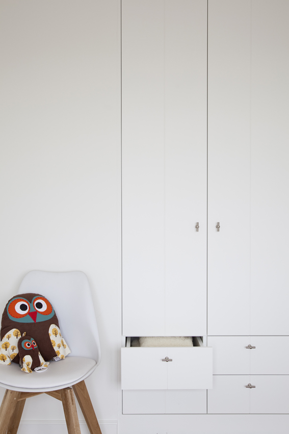 Witte kinderkamerkast met lade en stoel met uilkussen