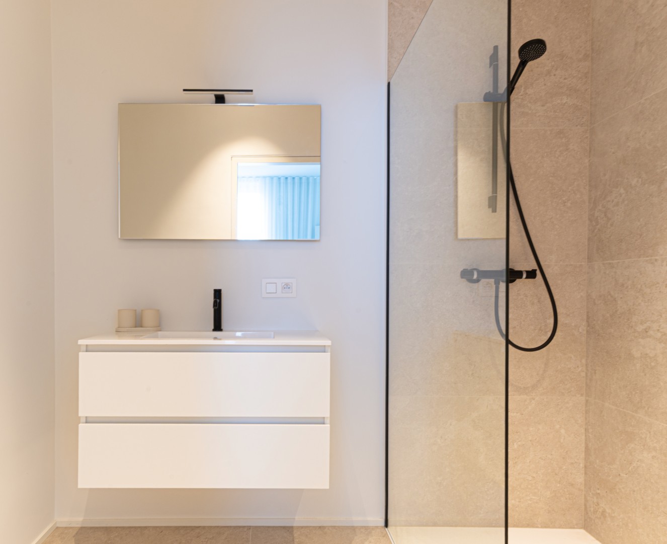 Badkamer met wit wastafelmeubel spiegel en inloopdouche