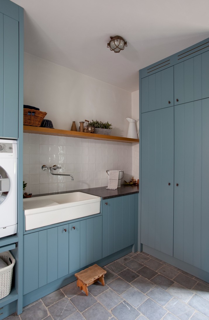 Blauwe wasplaats met spoelbak wasmachine en tegelvloer