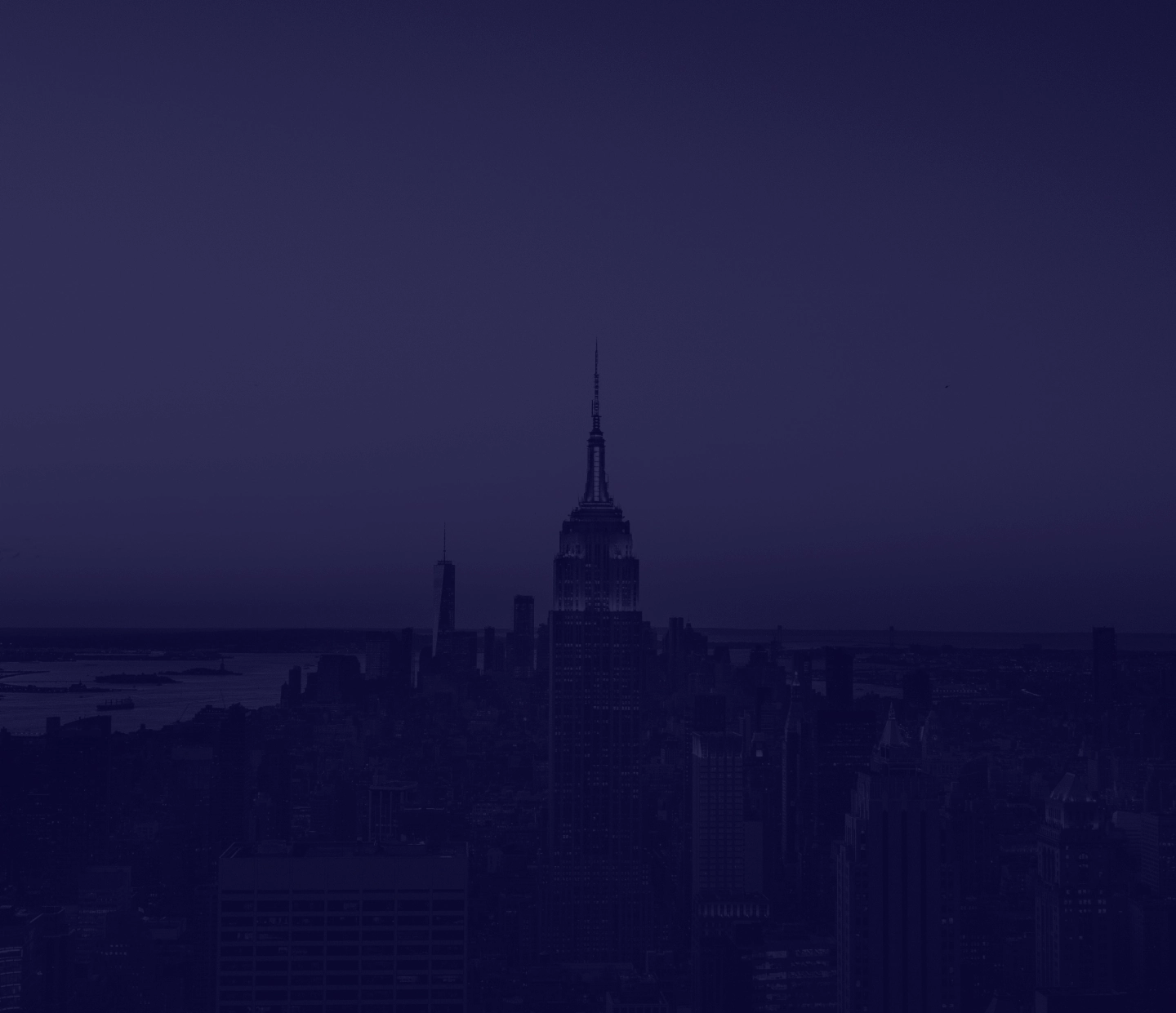 Nighttime cityscape featuring the Empire State Building illuminated against a dark sky.