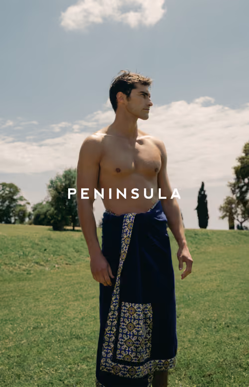 Peninsula Swim&Wear: model holding a patterned towel in a garden