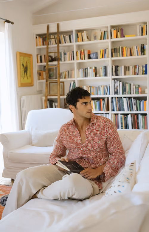 Peninsula Swim&Wear: model in a red shirt reading on a sofa in a library
