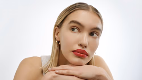 Infinity Cosmetics: model with red lipstick resting her chin on her hands