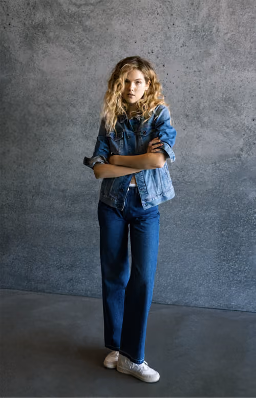 Gas Jeans: model in a denim jacket and jeans against a concrete wall