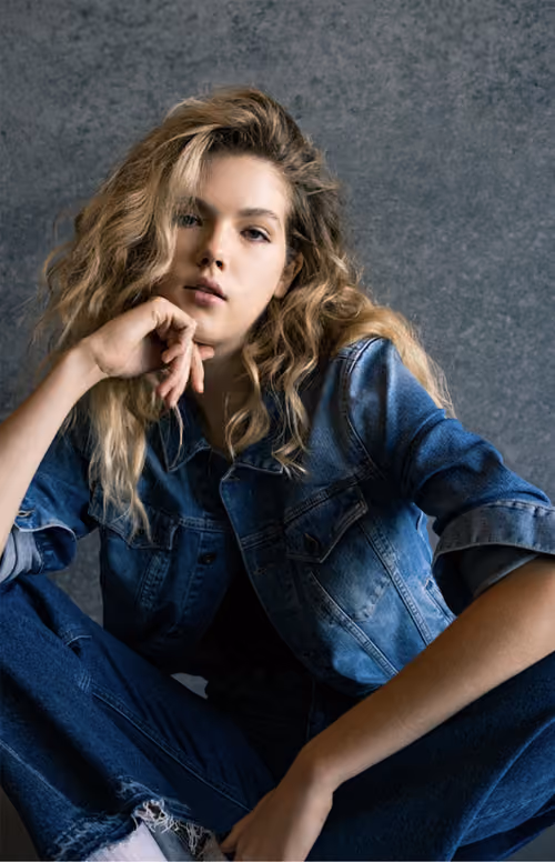 Gas Jeans: model with curly hair in denim, seated