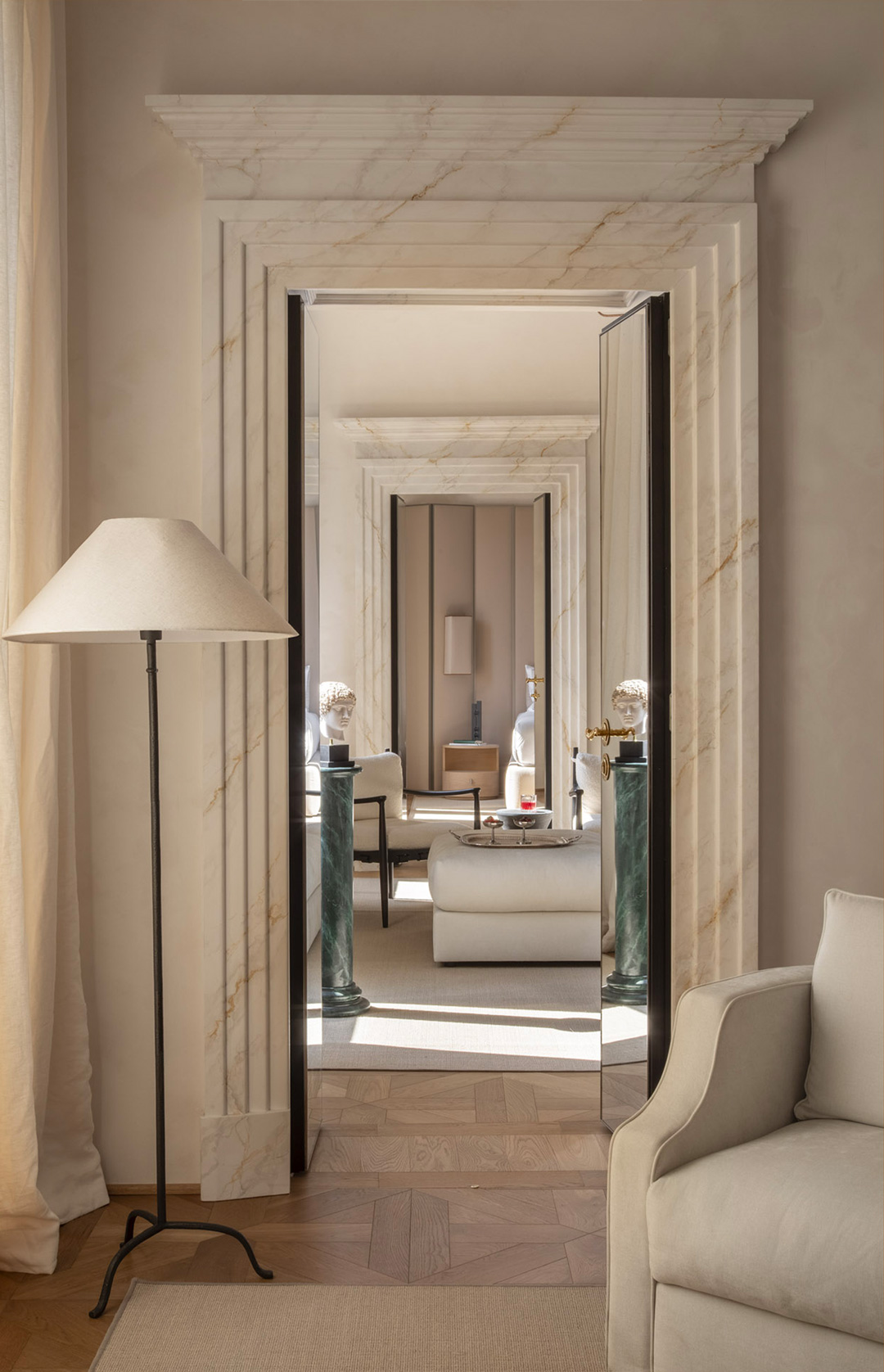 Casa Naman: marble doorway framing a corridor of rooms, floor lamp in the foreground