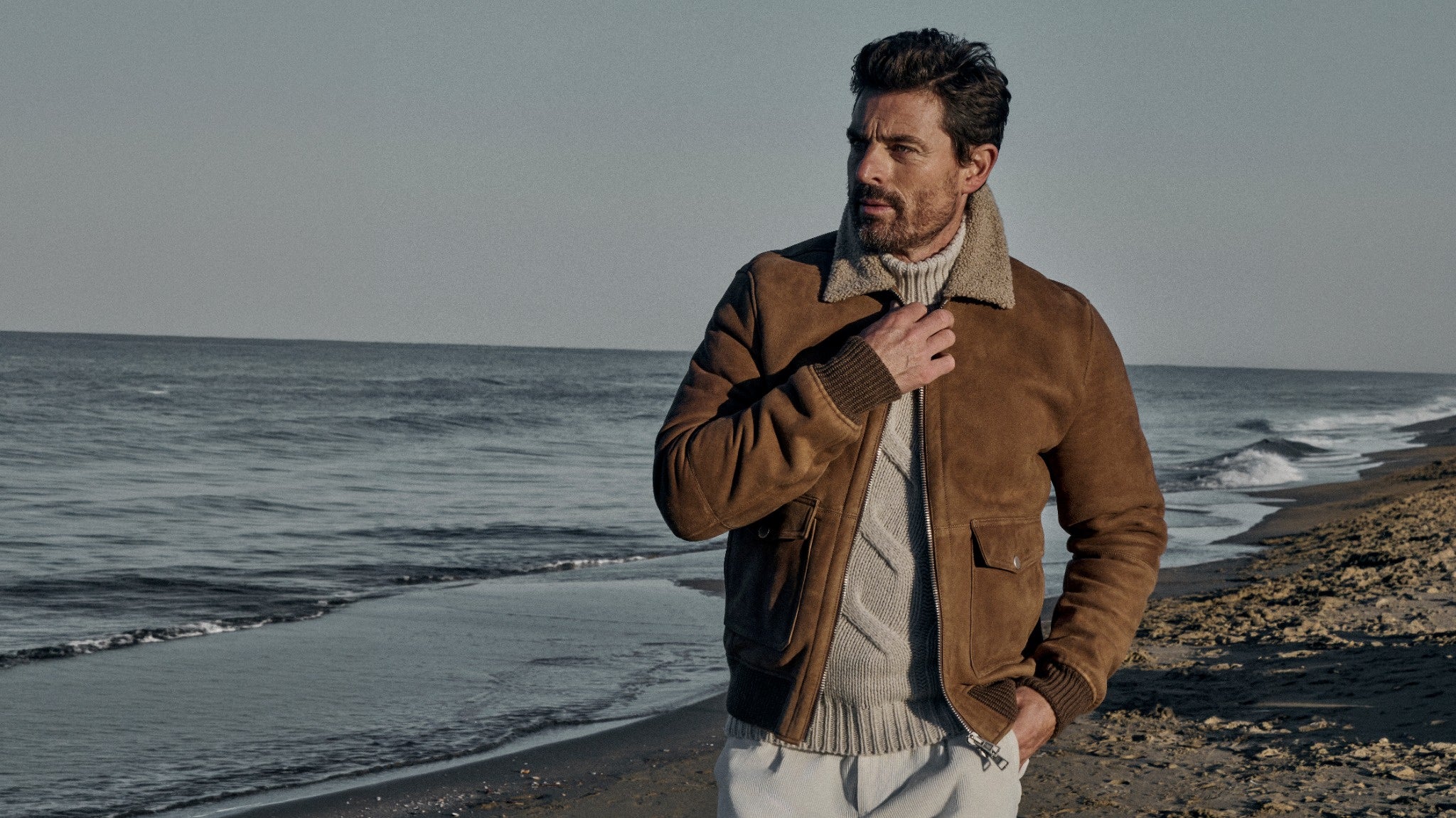 Paul Taylor FW26 campaign: model in a suede shearling bomber on the beach