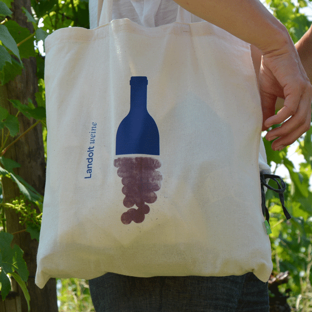 Stoffbeutel mit Logo von Landoltweine als Aufdruck, ein Mensch der mit dieser Tasche in den Rebbergen umher läuft