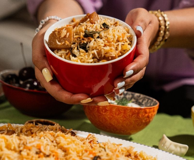 An individual holding Biryani for the SHN's recipe campaign, encouraging people to submit their recipes.