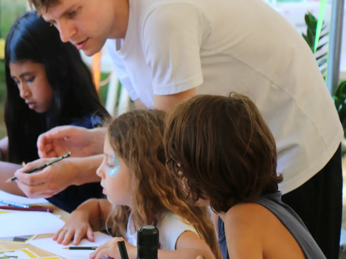 Trois enfants accompagnés par un artiste-enseignant pour réaliser un dessin