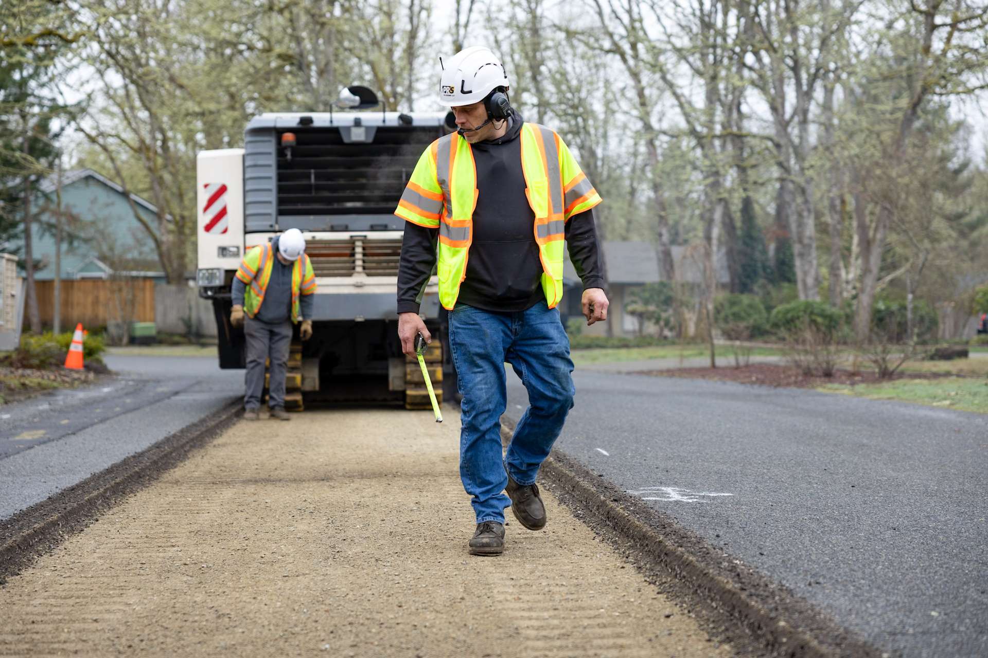 PR Systems crew measuring and preparing road surface during asphalt milling project in a residential neighborhood.