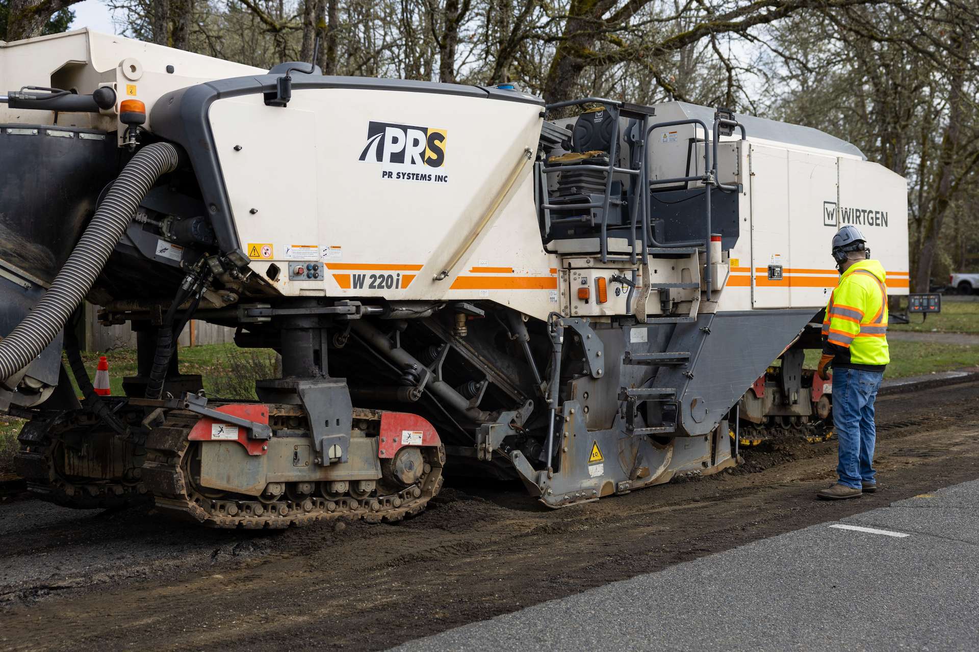 Side view of Wirtgen W 220i milling machine with PR Systems branding during road grinding operation.