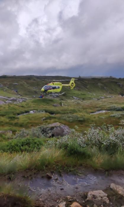 A helicopter flying over a grassy fieldDescription automatically generated