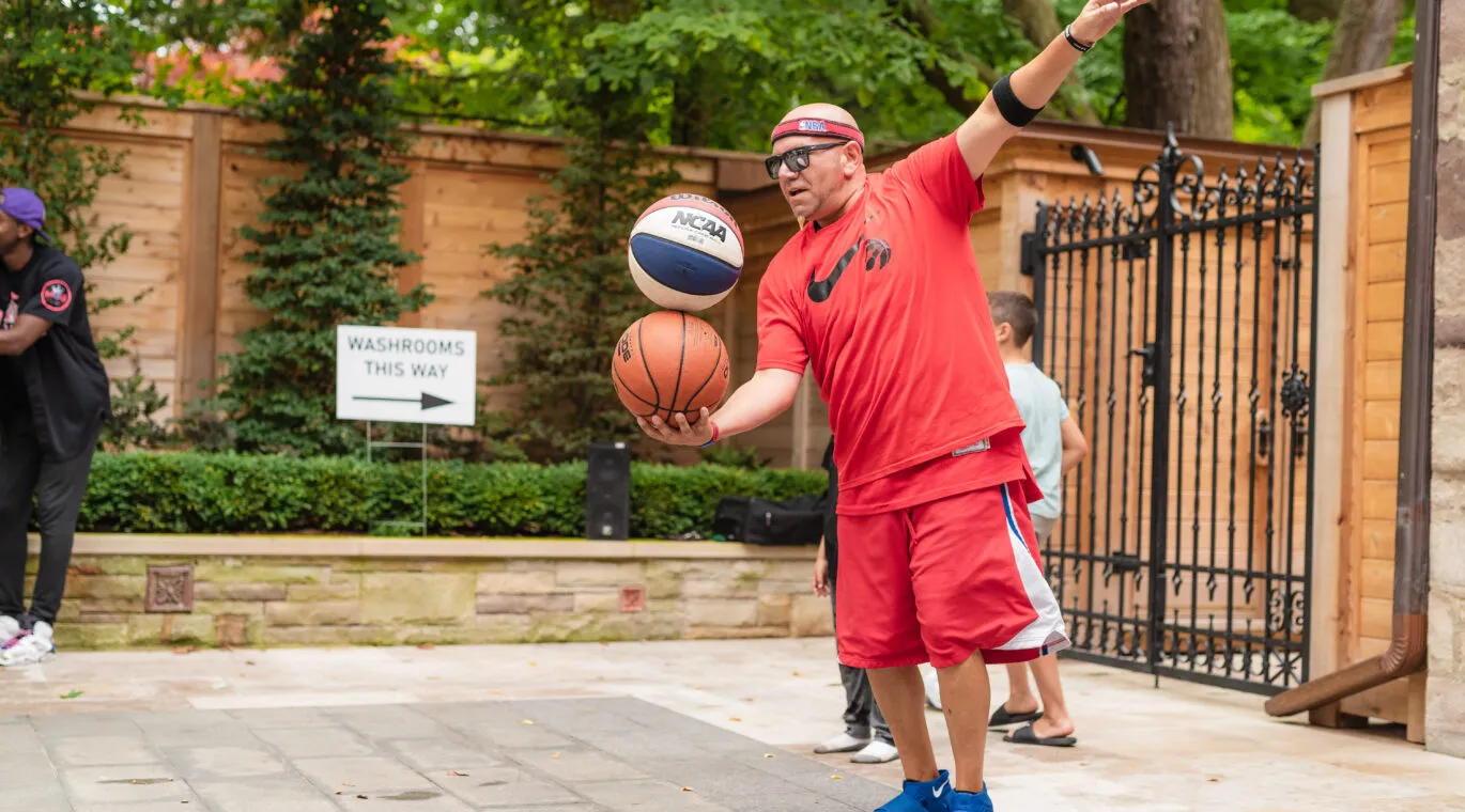 person juggling two basketballs at a party