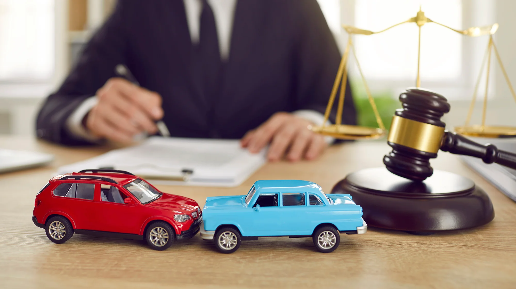 A image of two car toys and a lawyer in the background.