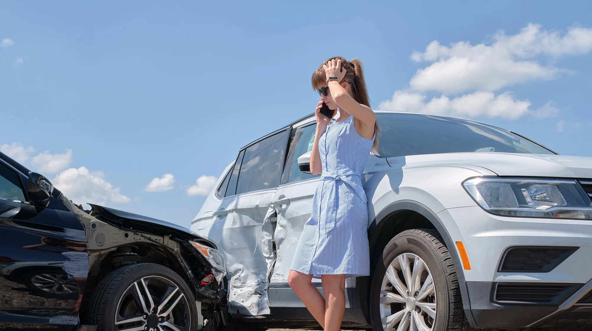 Una mujer parada junto a su automóvil después de un accidente automovilístico.