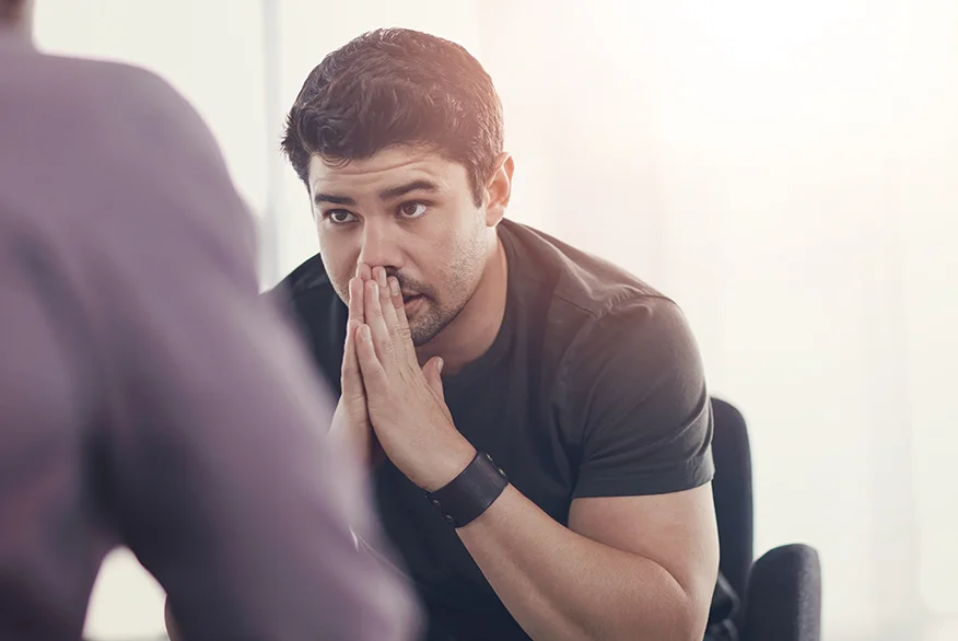 A sad man talking with someone.