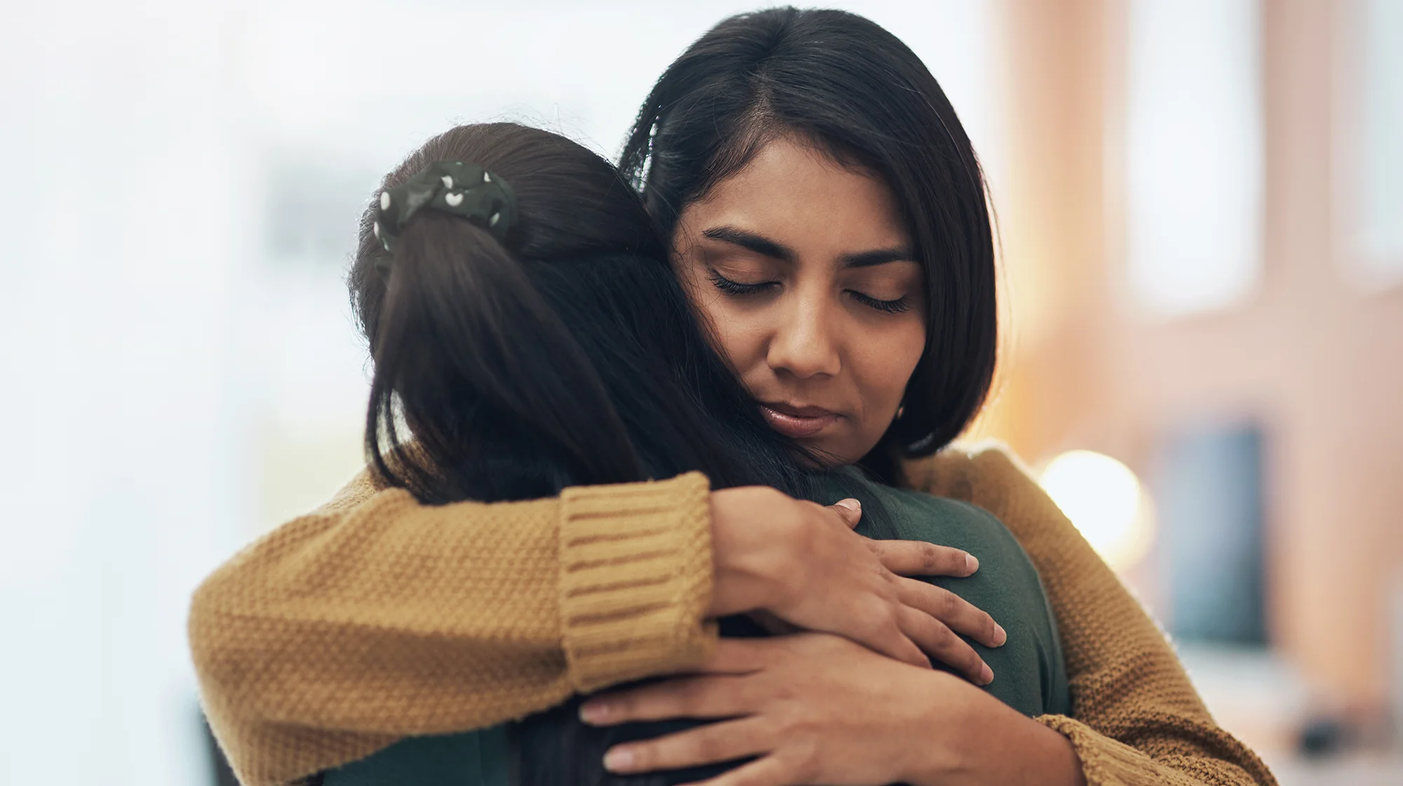 Una mujer triste abraza a otra.