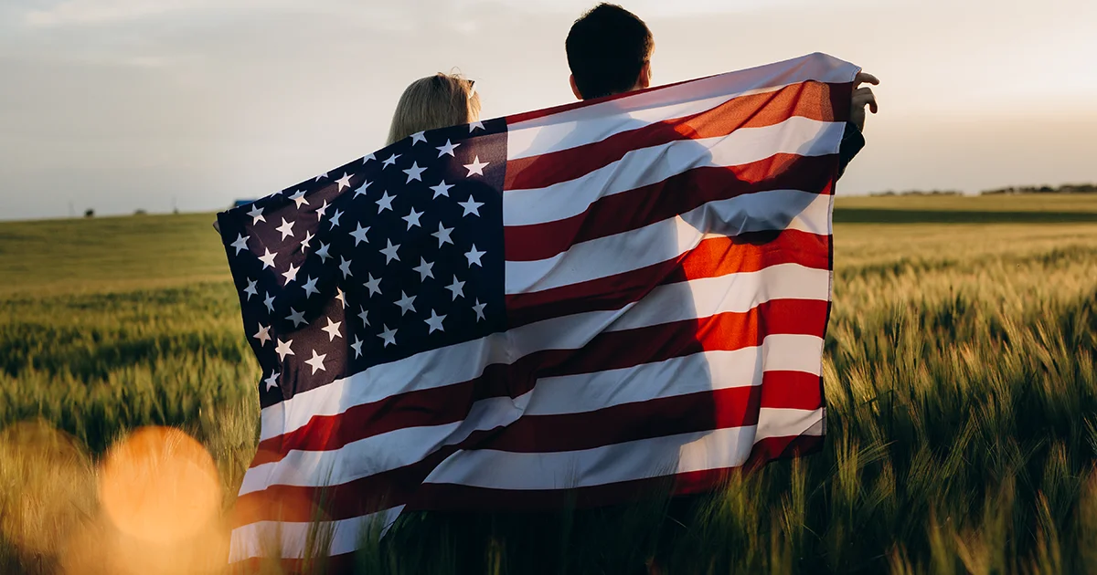Una pareja con bandera estadounidense al atardecer.