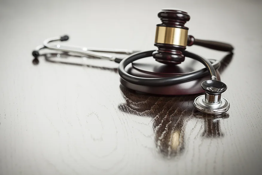 Gavel and Stethoscope on Reflective Wooden Table.