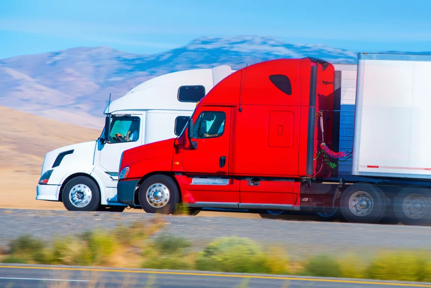 Two semi trucks speeding on the highway.
