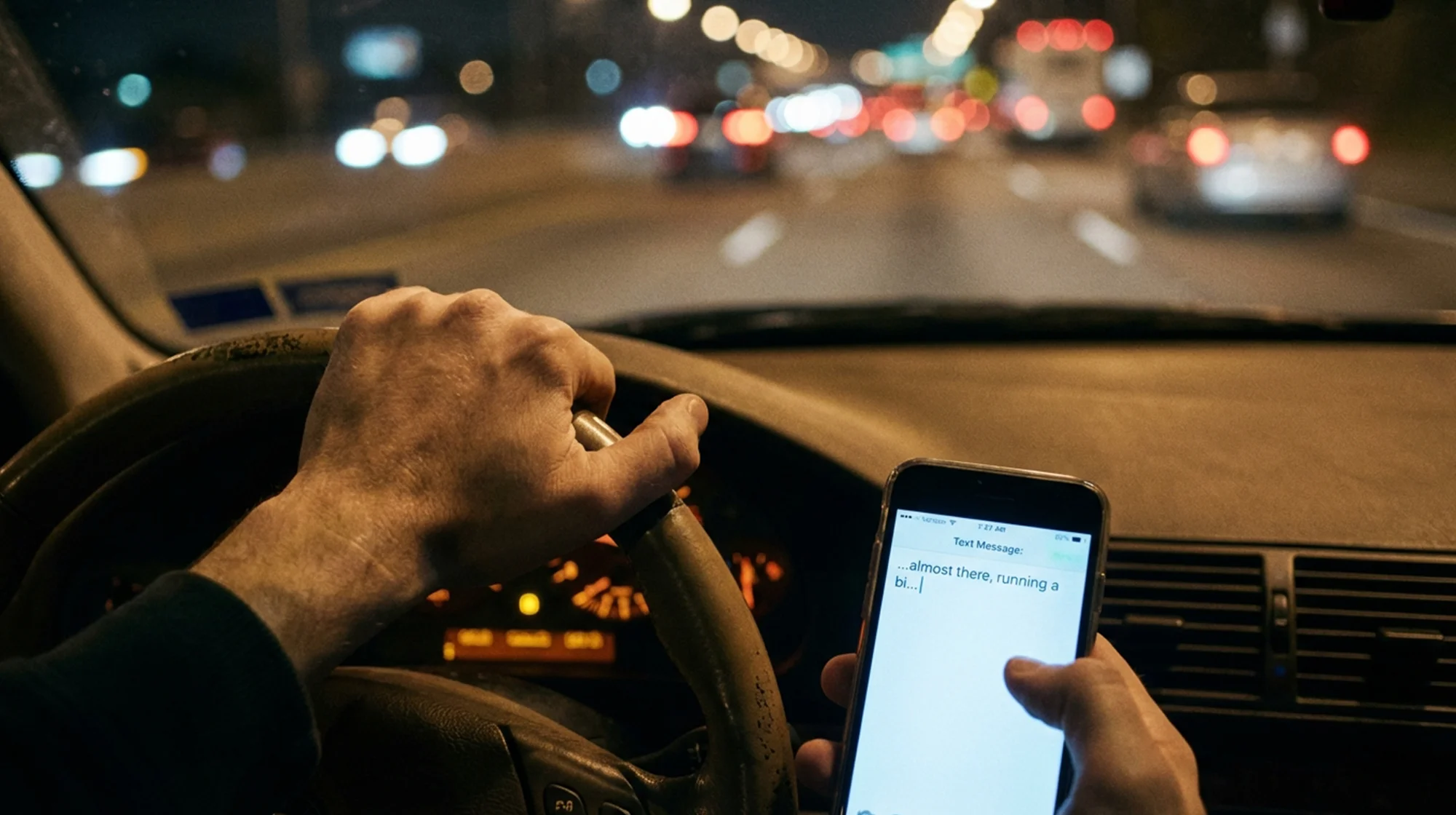 View of someone texting while driving a car.