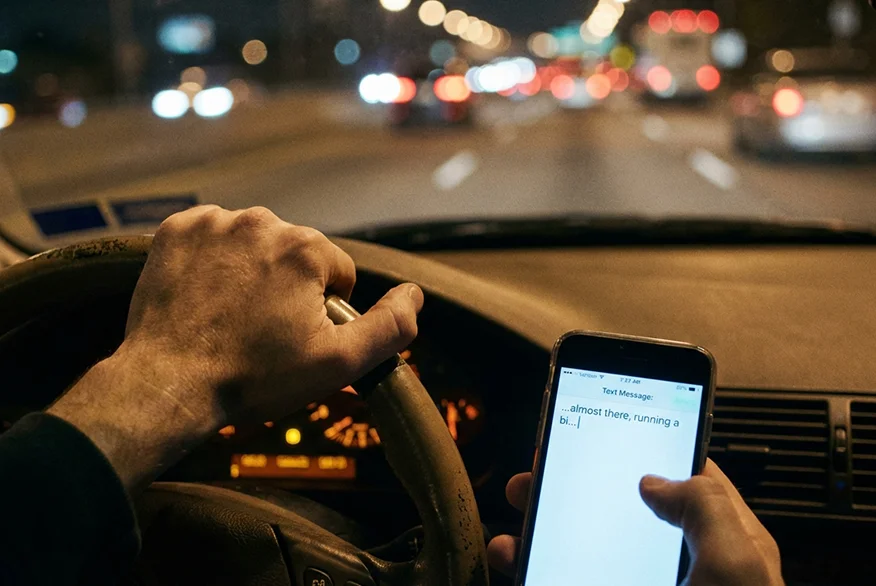 View of someone texting while driving a car.
