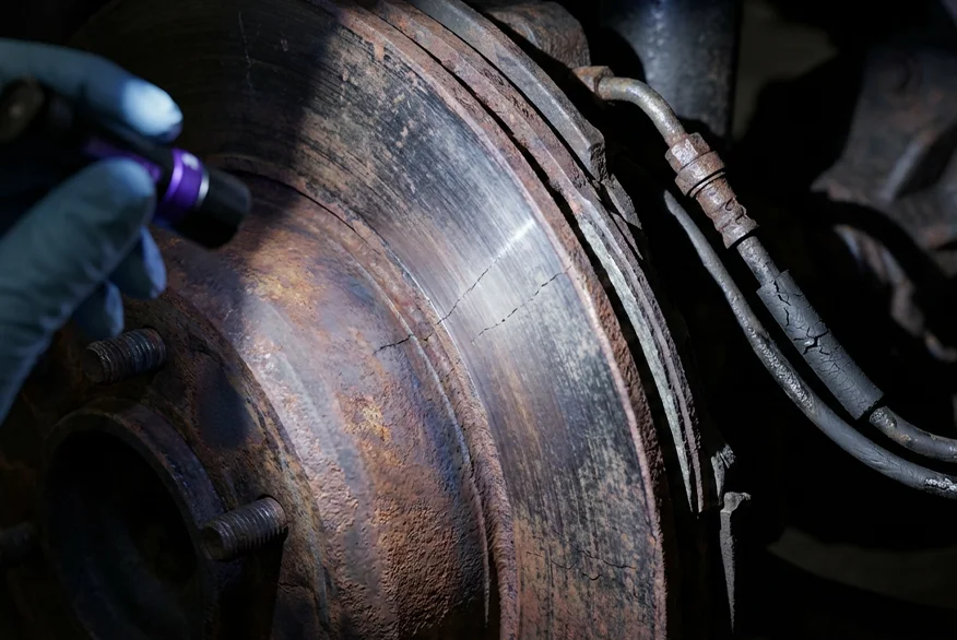 A close up picture of someone inspecting a damaged break disk of a semi truck.