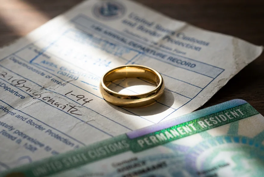 Un anillo de bodas cerca de una tarjeta de residente permanente y un formulario I-94.