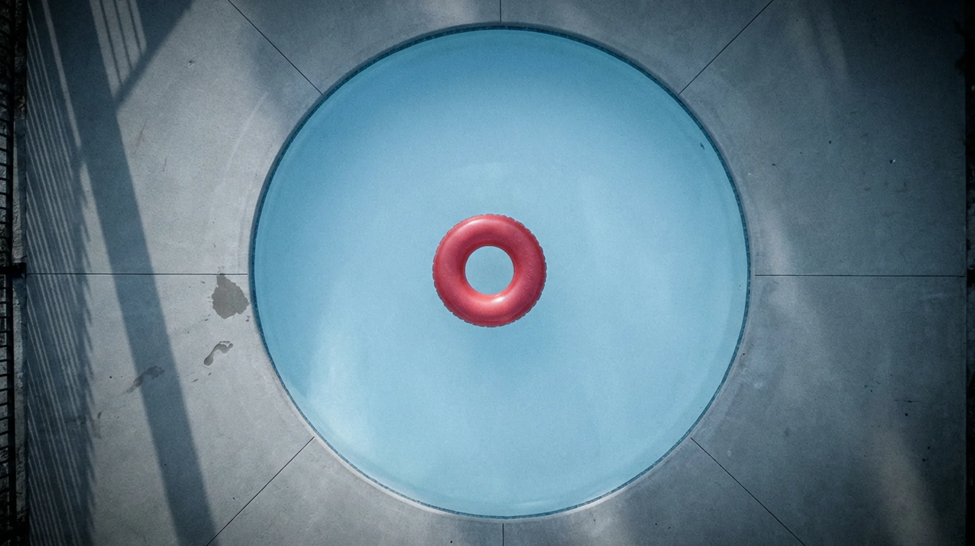 Vista de arriba hacia abajo de una piscina circular con un anillo inflable rojo.