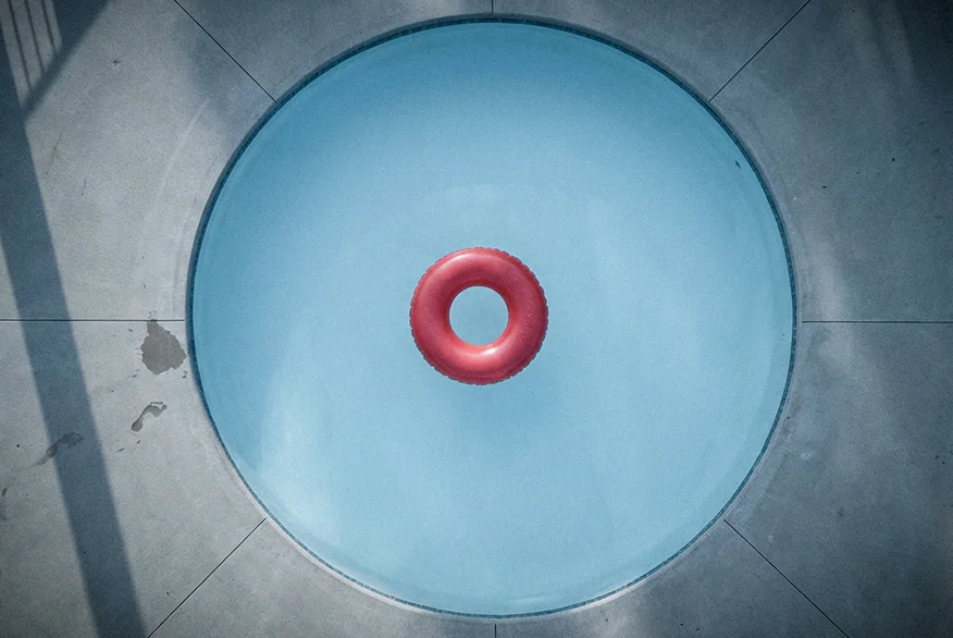 Vista de arriba hacia abajo de una piscina circular con un anillo inflable rojo.