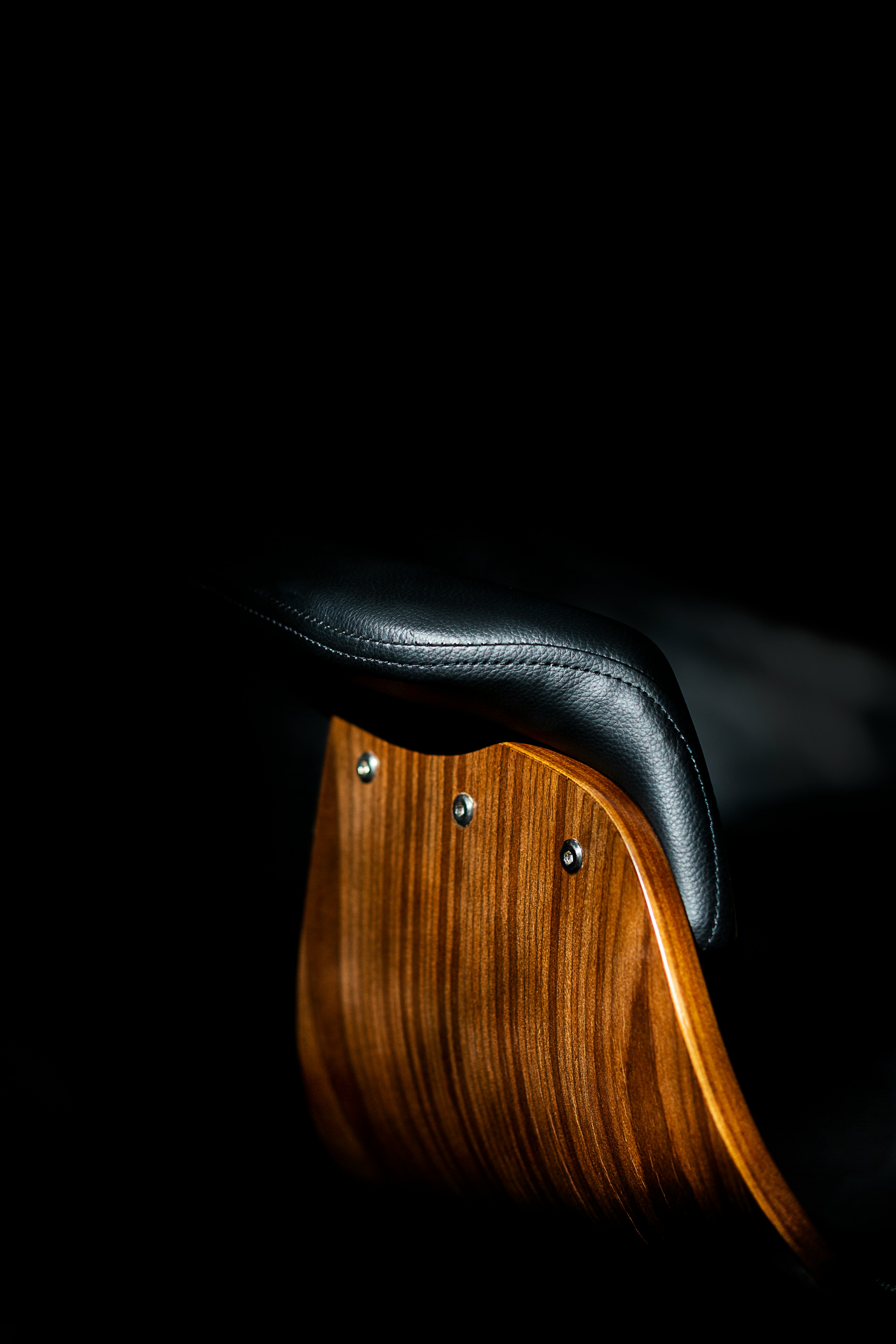 The back of a wood, and black leather chair, dramatic shot