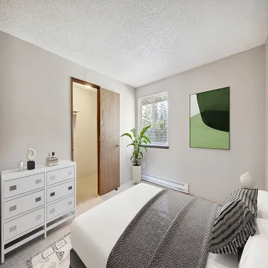 Minimalist bedroom with white bed, gray blanket, green plant by window, and abstract green wall art.