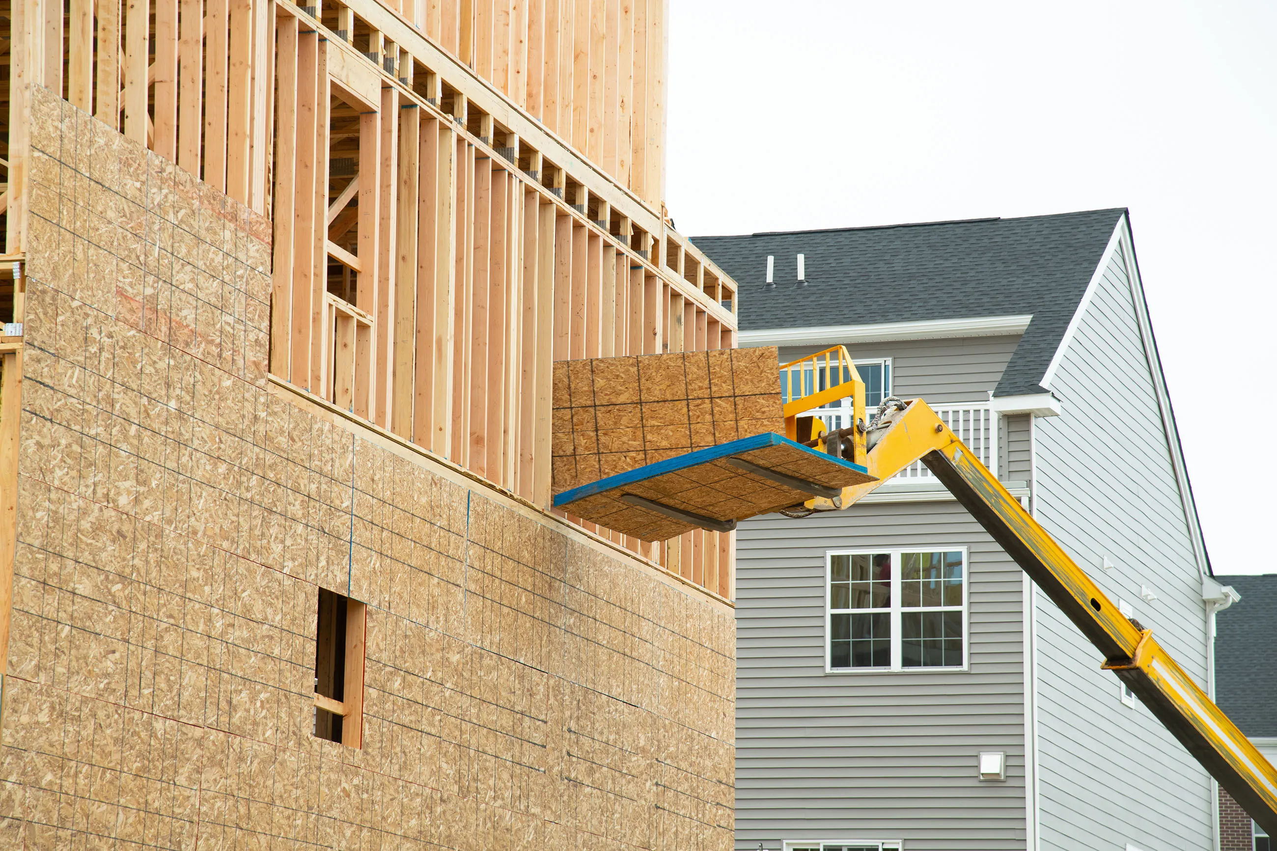 Forklift at a construction site of a plywood house wood with new frame work 
