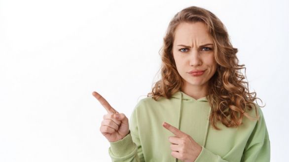 Une femme pointe son doigt vers un objet hors champ, semblant attirer l'attention sur quelque chose d'important.