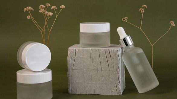 Trois bocaux transparents avec des couvercles blancs et une petite bouteille à côté.