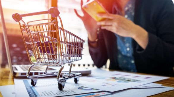 Une femme utilise son téléphone en étant assise devant un chariot de courses.
