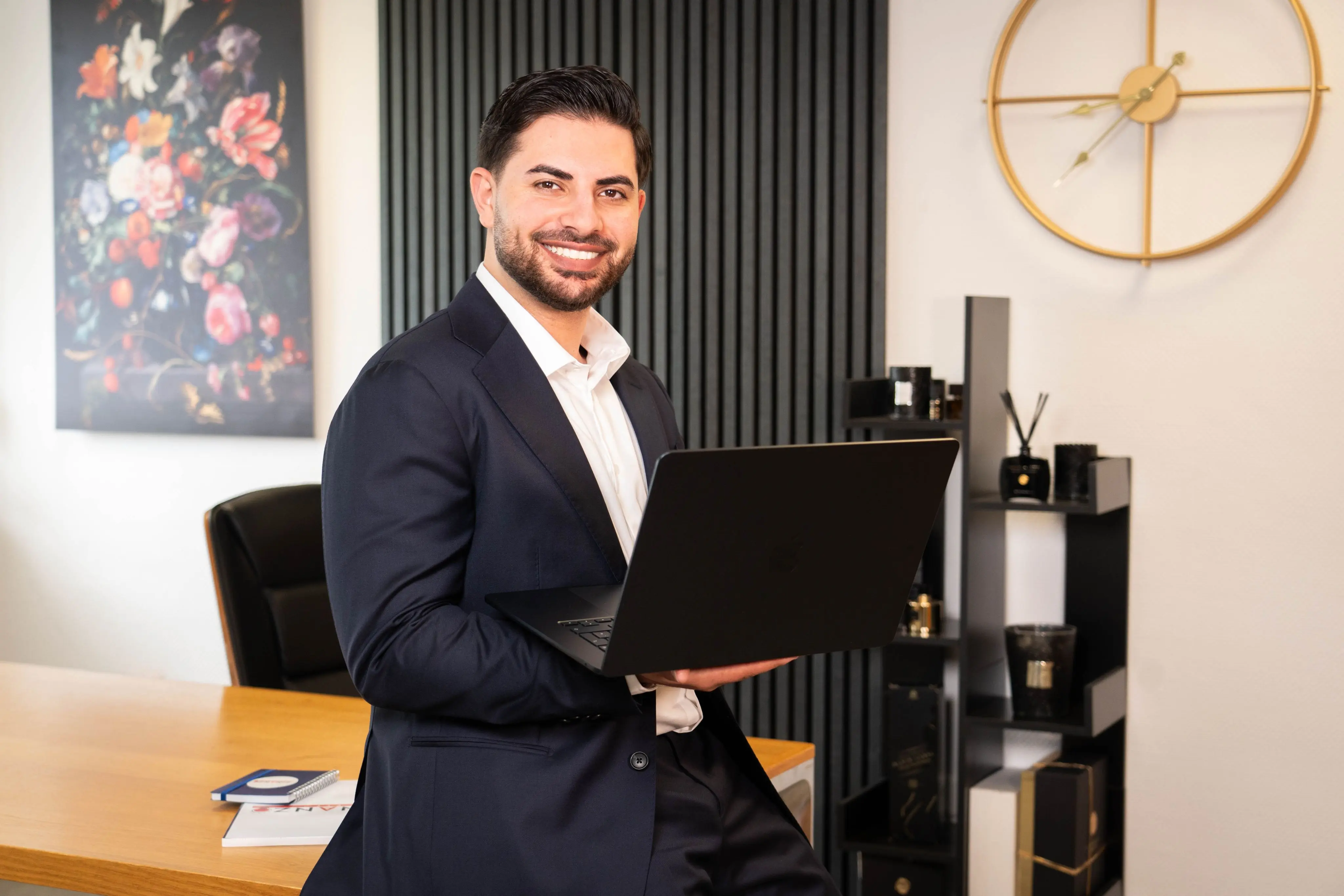 Nasim Birawi mit einem Laptop in der Hand. Er lächelt dabei freundlich.