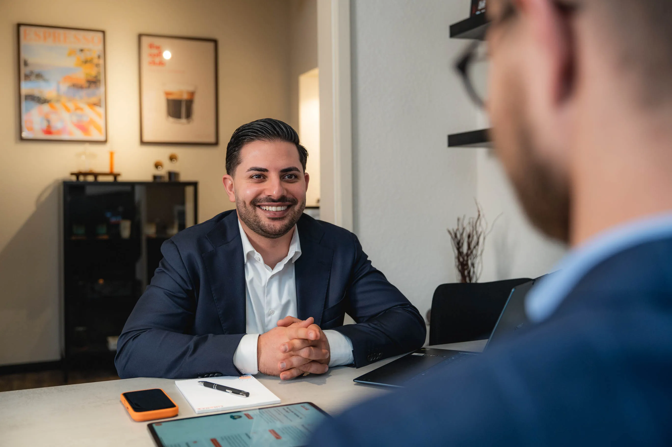 Nasim sitzt an einem Schreibtisch und spricht mit Tim.