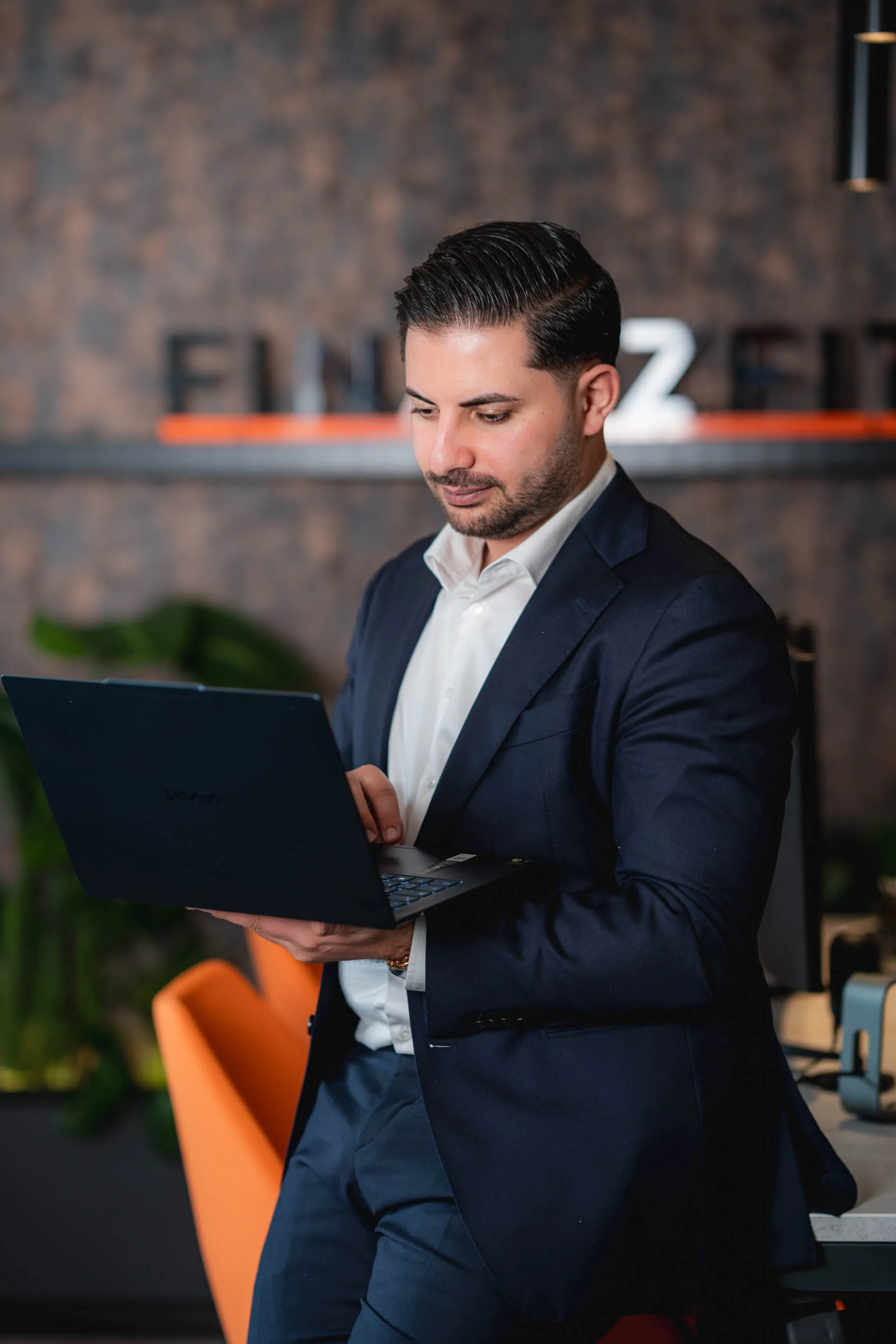 Nasim in blauem Anzug, der stehend auf einen Laptop schaut und tippt.