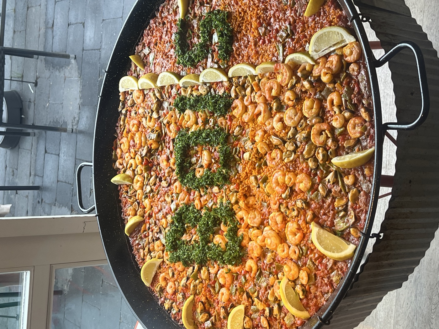 Paella met de bedrijfsnaam in peterselie op een bedrijfsuitje
